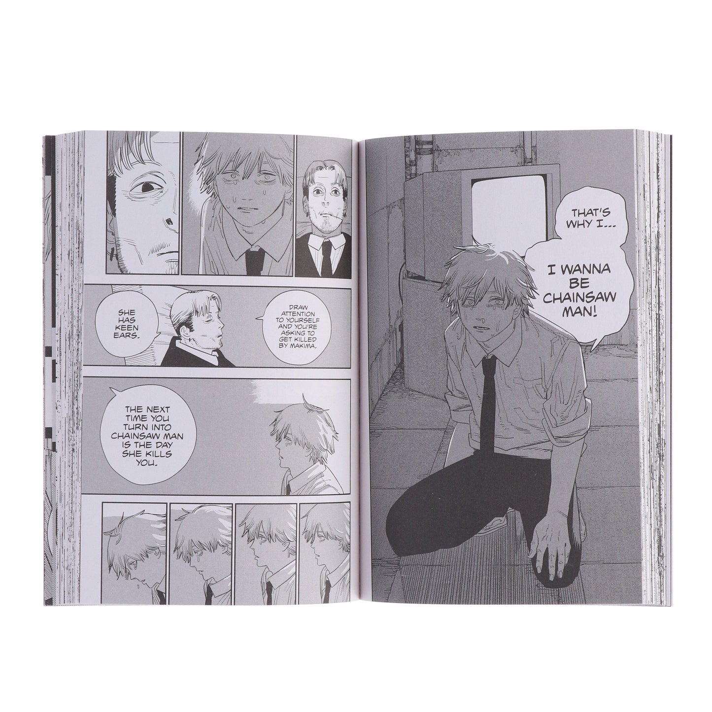 Manga book open to a page with character panels and dialogue bubbles.