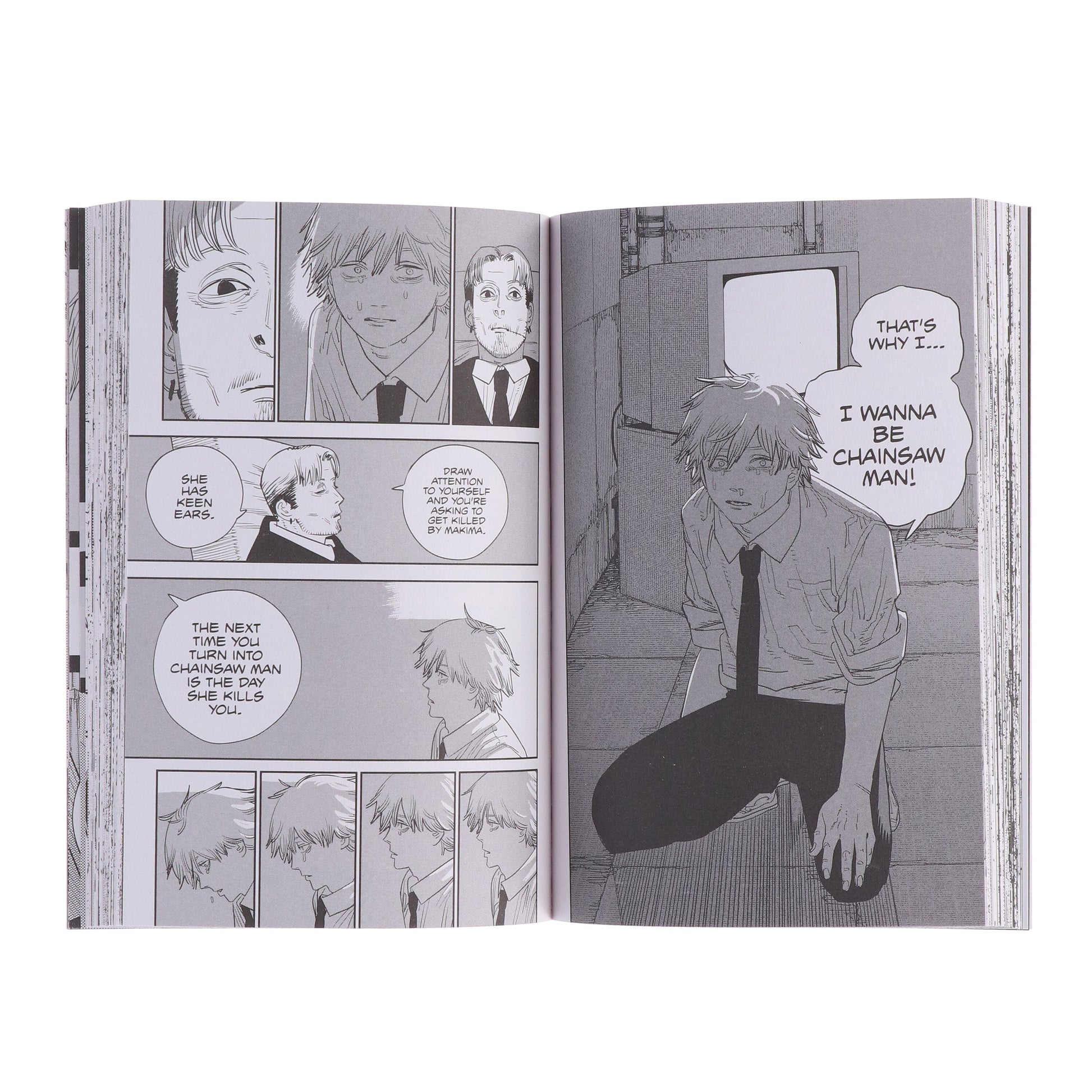 Manga book open to a page with character panels and dialogue bubbles.